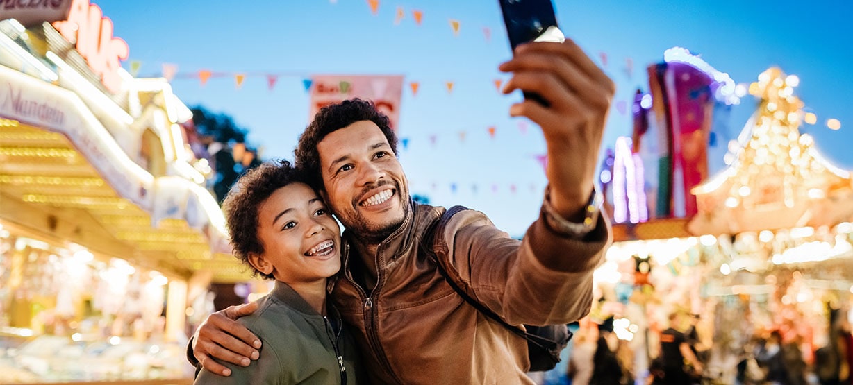 a father with his son at the funfair taking a selfie.