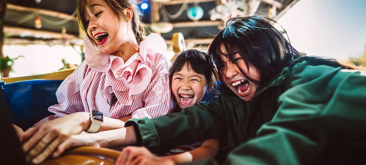 family having fun on a spinning teacup ride in the amusement park