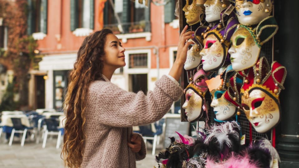 A Woman admiring the colourful masks from the venice carnival.