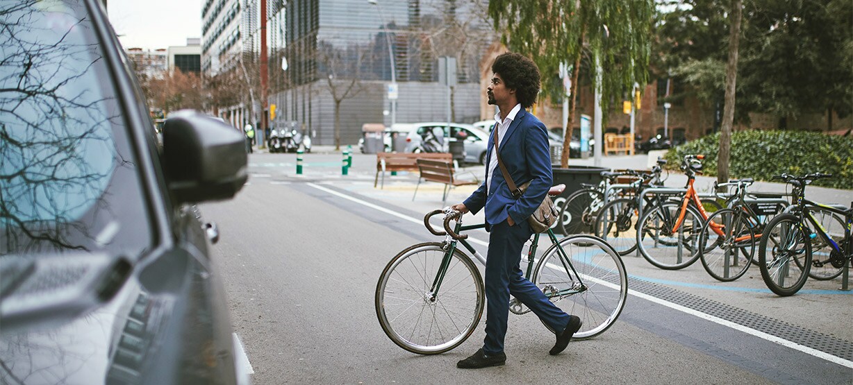 Man crossing a street with his bicycle.