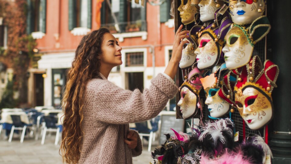 Uma mulher a admirar máscaras coloridas do carnaval de veneza