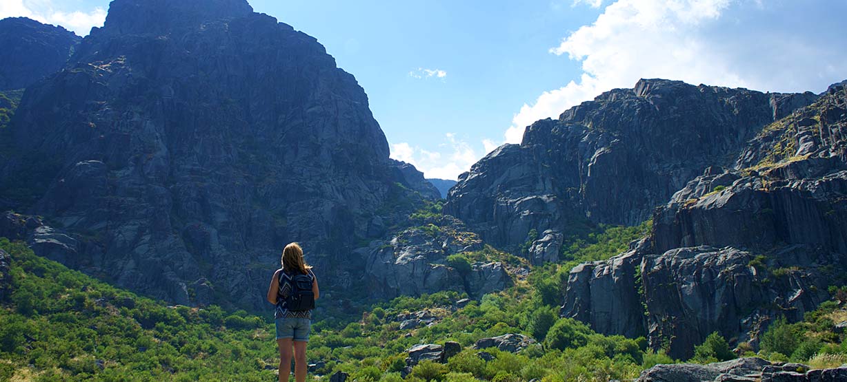 Rapariga com mochila a olhar para as montanhas da Serra da Estrela